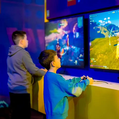 Twee jongens spelen een LEGO® game op grote schermen