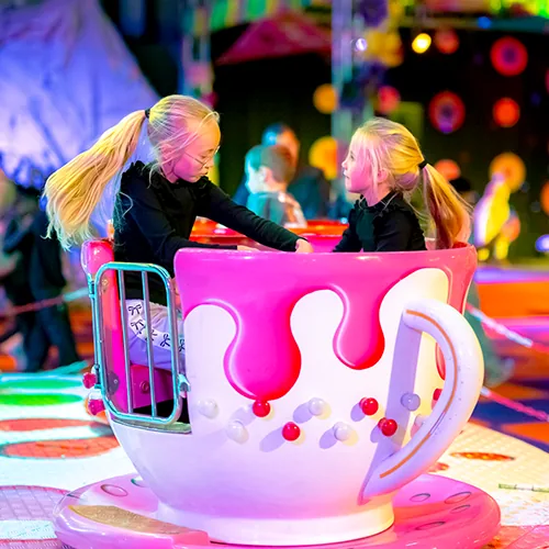 Twee meisjes in een draaiend theekopje op de kermis