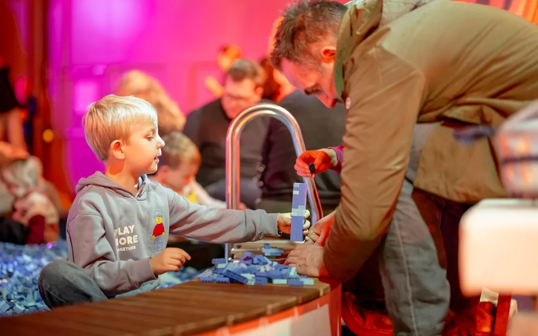 Een jongen bouwt aan een speeltafel vol LEGO stenen op LEGO World