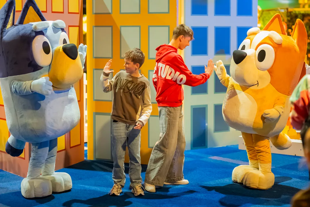 Twee kinderen begroeten de LEGO figuren van Bluey en Bingo op LEGO World