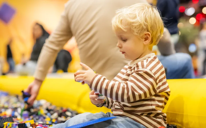 Een peuter speelt met LEGO DUPLO stenen in een grote speelbak.