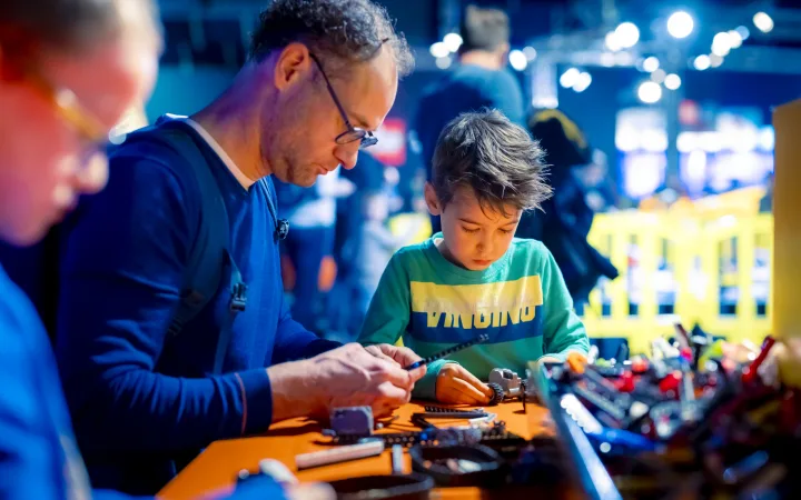Een vader en zoon bouwen samen aan een klein LEGO Technic model.